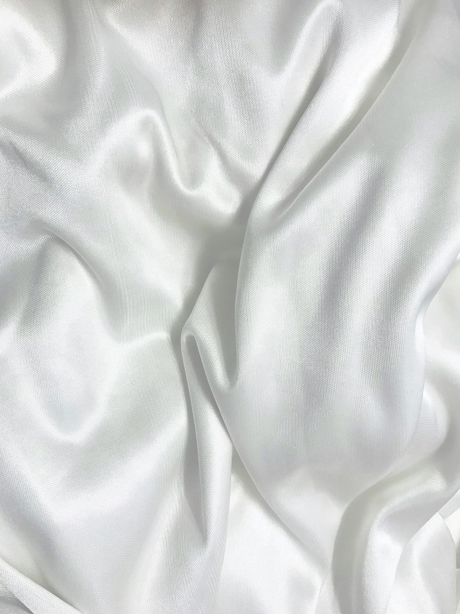 Detaliu de material textil alb cu textură lucioasă – fotografie realizată în cadrul selecției GYMTUNED la Texworld Paris.