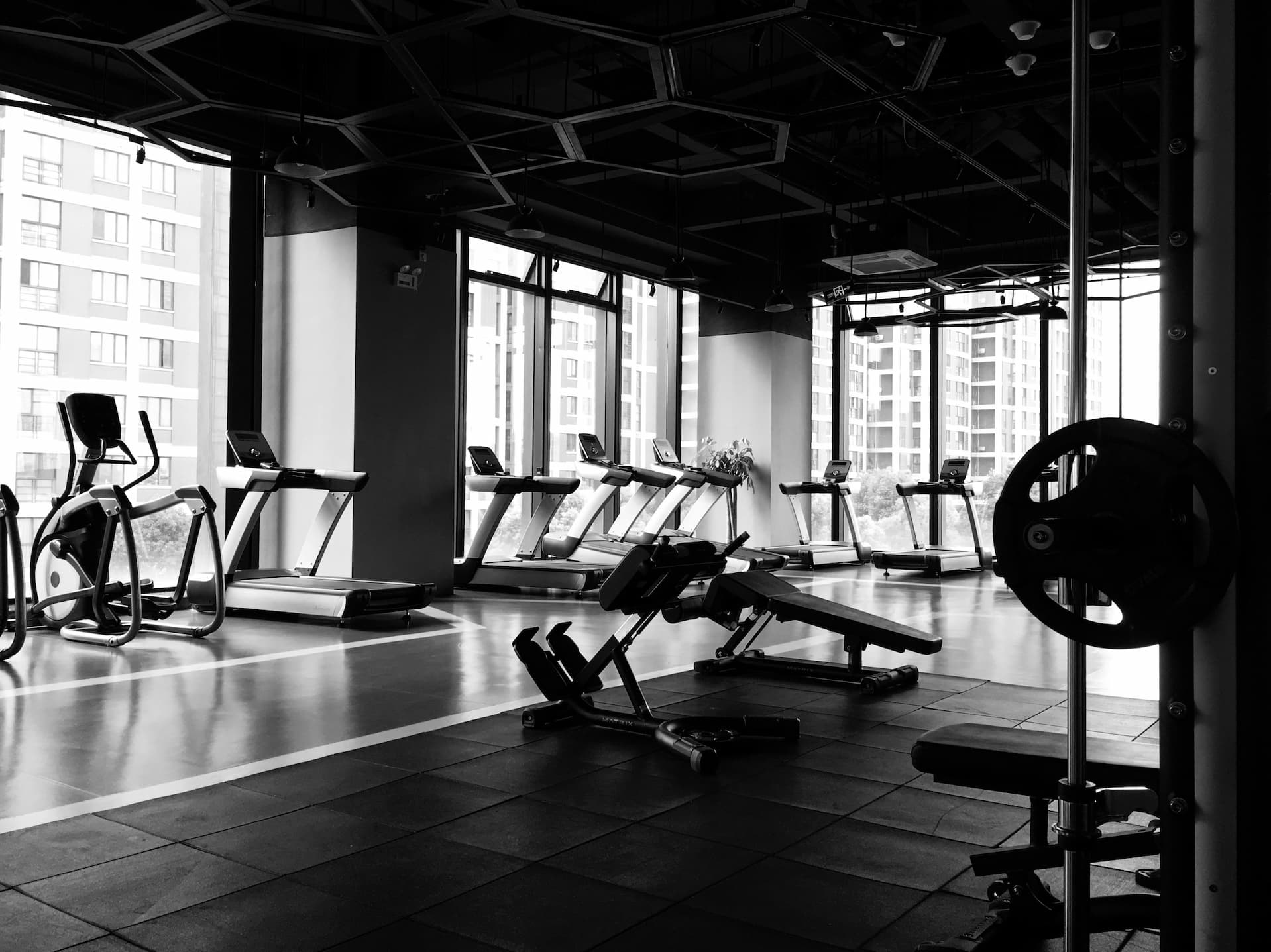 Sală de fitness urbană, luminată natural – aparate de cardio și greutăți într-un cadru alb-negru. Imagine inspirațională folosită de GYMTUNED.