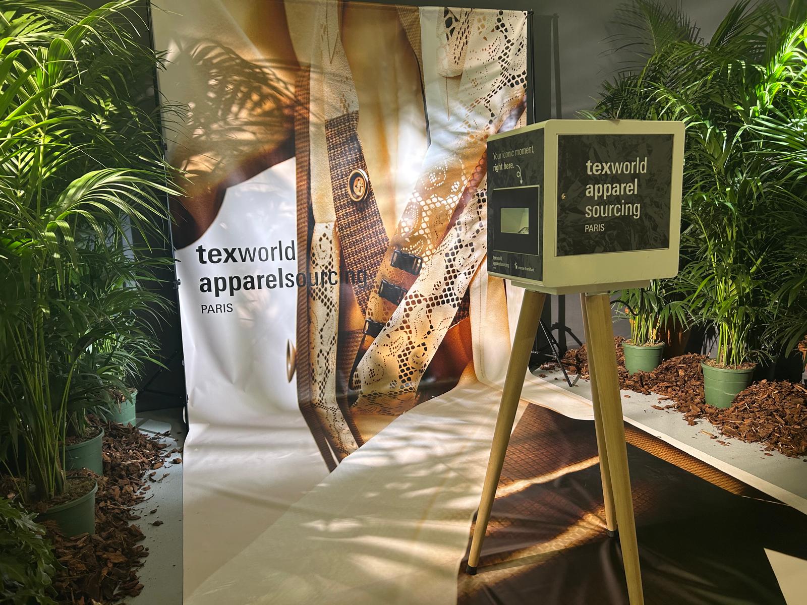 Colț de fotografie decorat la Texworld Paris – zonă creativă pentru vizitatori, cu fundal textil și plante, parte din experiența GYMTUNED în căutarea materialelor.