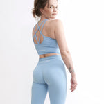 Set Original by GYMTUNED în albastru pastel – bustieră sport cu bretele duble încrucișate și colanți seamless modelatori pentru sala si fitness, vedere din spate cu logo vizibil
