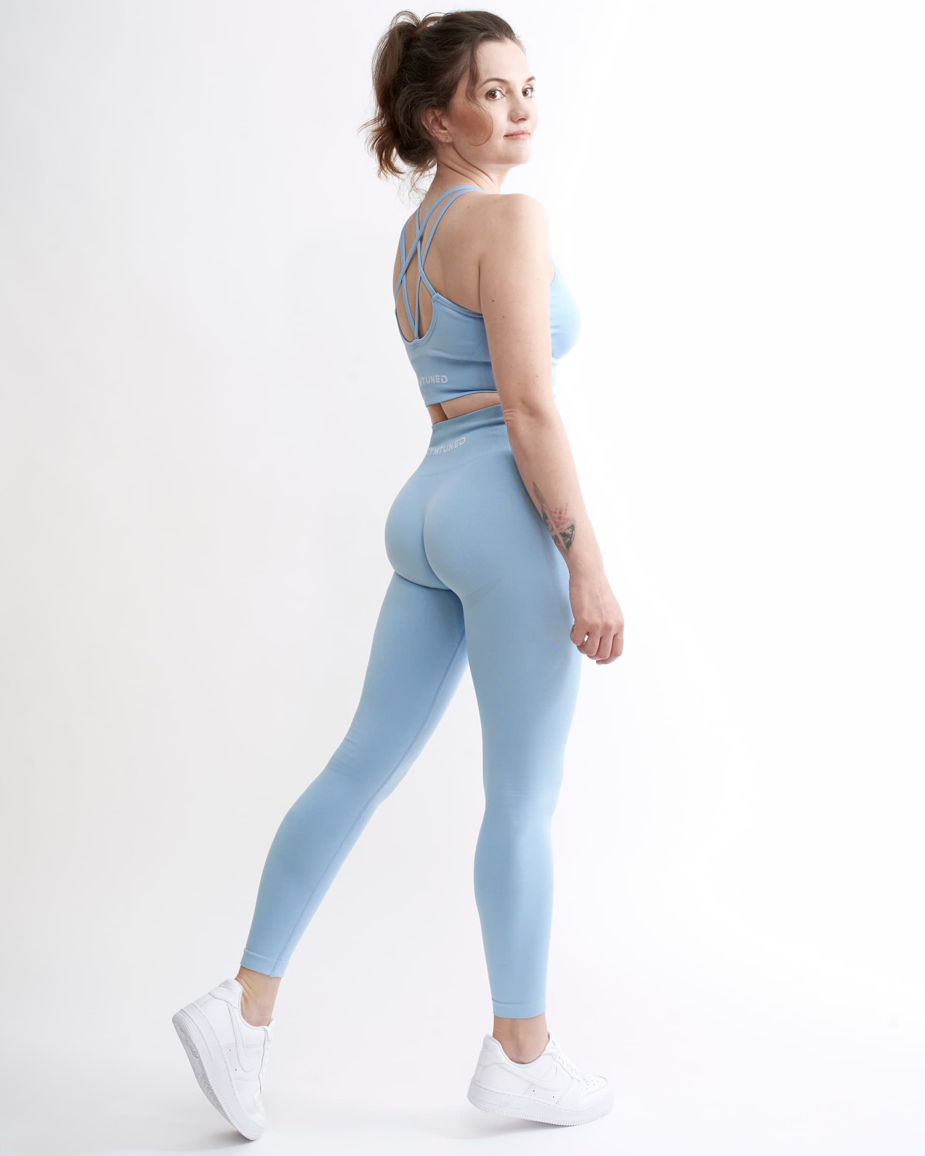 Set Original by Gymtuned în albastru pastel – vedere din spate cu bustieră sport pentru fitness si sala cu bretele încrucișate și colanți modelatori seamless, purtate de model