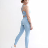 Set Original by Gymtuned în albastru pastel – vedere din spate cu bustieră sport pentru fitness si sala cu bretele încrucișate și colanți modelatori seamless, purtate de model
