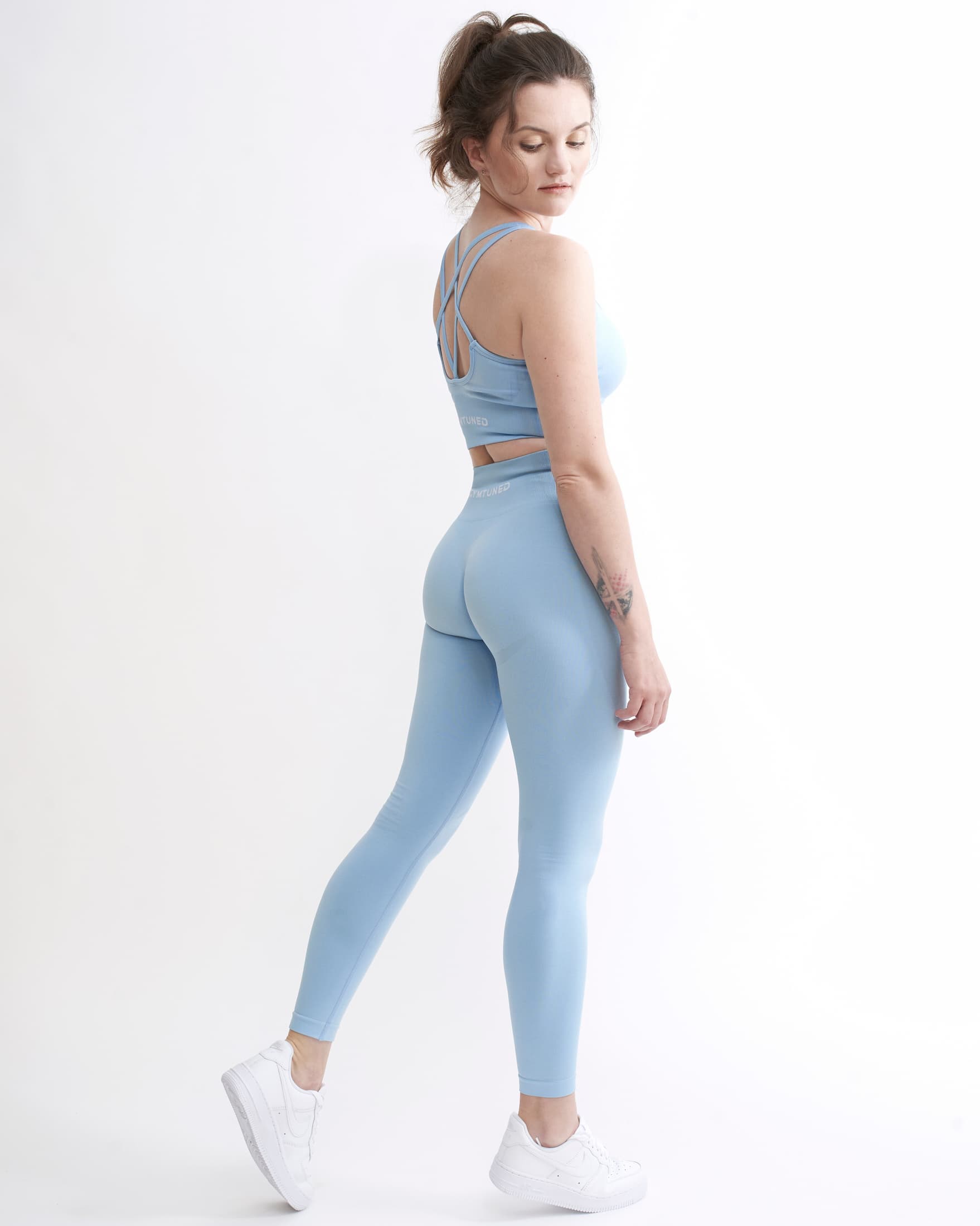 Set Original by Gymtuned în albastru pastel – vedere din spate cu bustieră sport pentru fitness si sala cu bretele încrucișate și colanți modelatori seamless, purtate de model