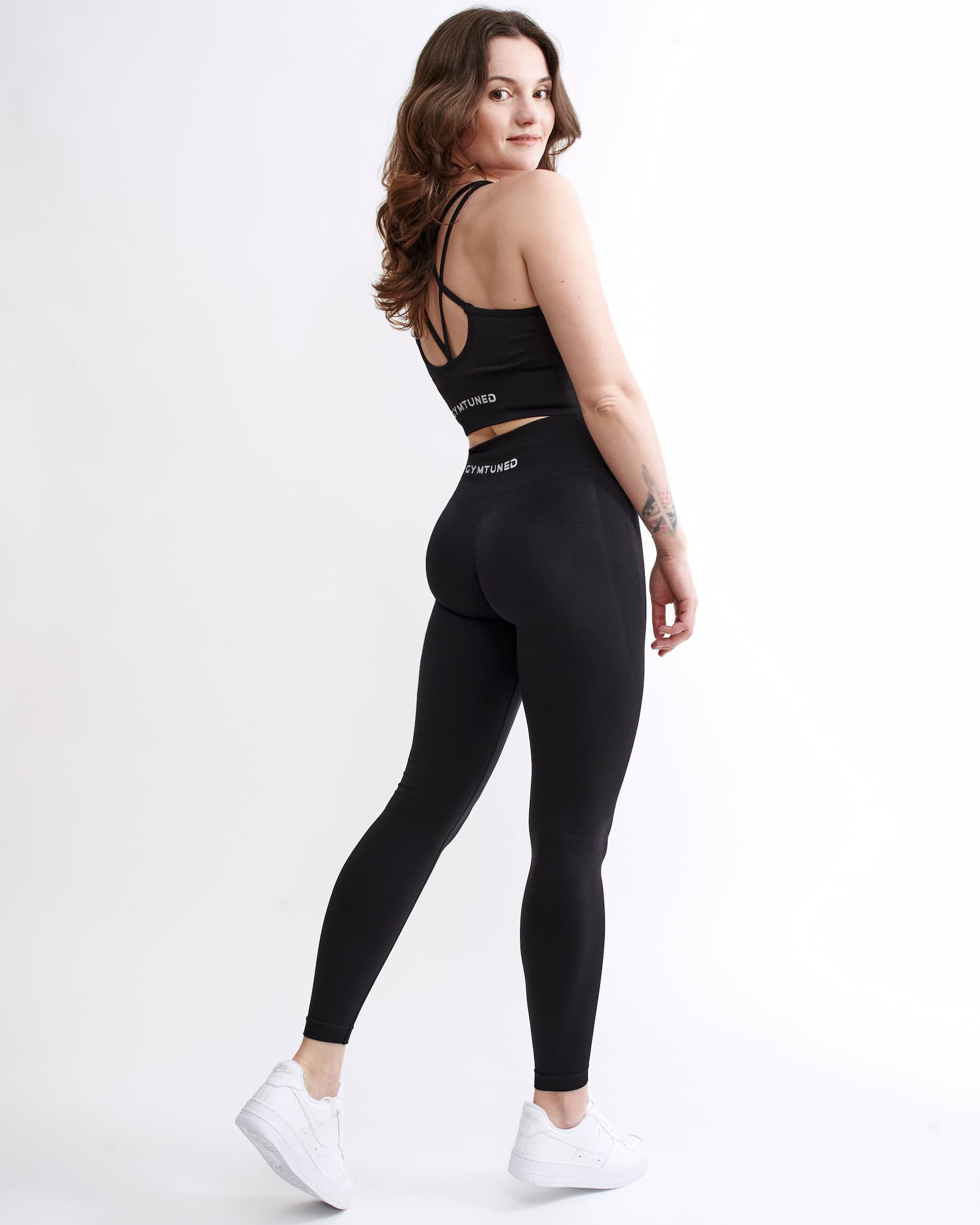 Set Original by Gymtuned în negru – vedere din spate cu bustieră sport pentru fitness si sala cu bretele încrucișate și colanți modelatori seamless, purtate de model